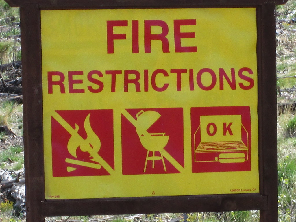A fire restrictions sign posted in a forest area.