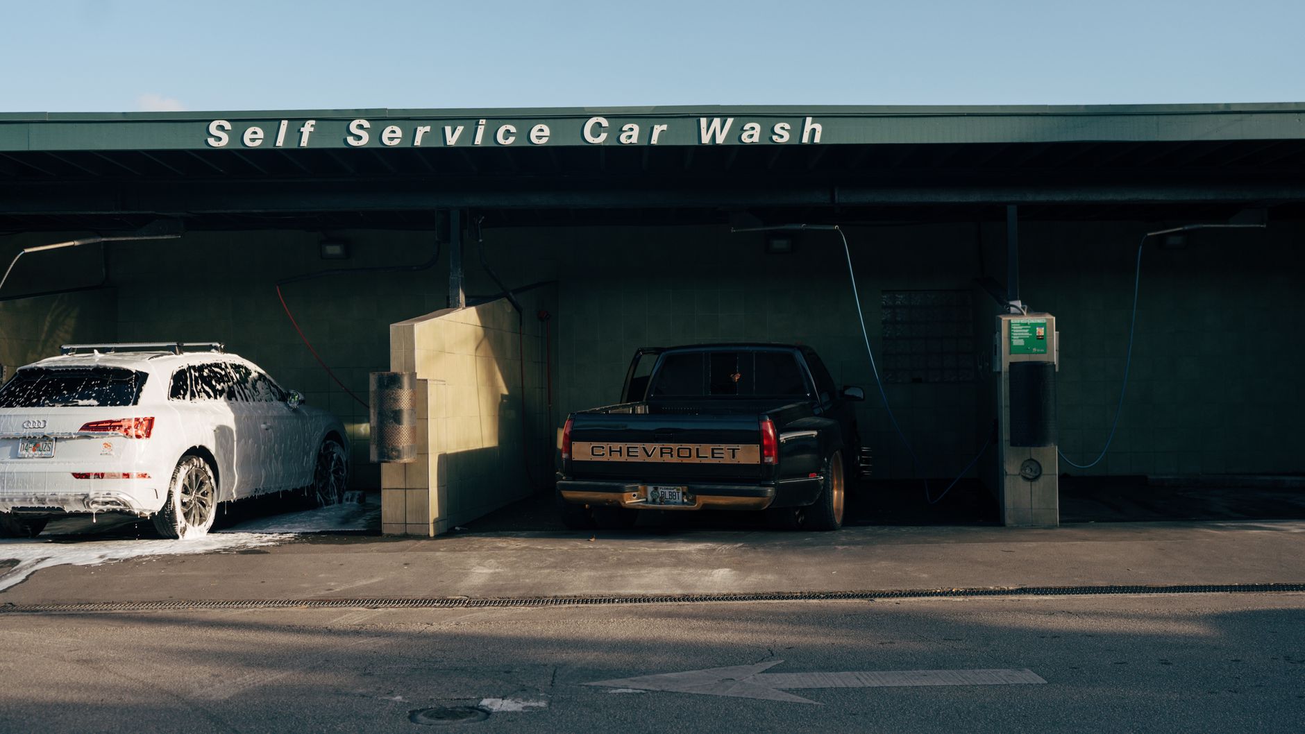 Vehicles are shown in the bays of a self-service car wash.