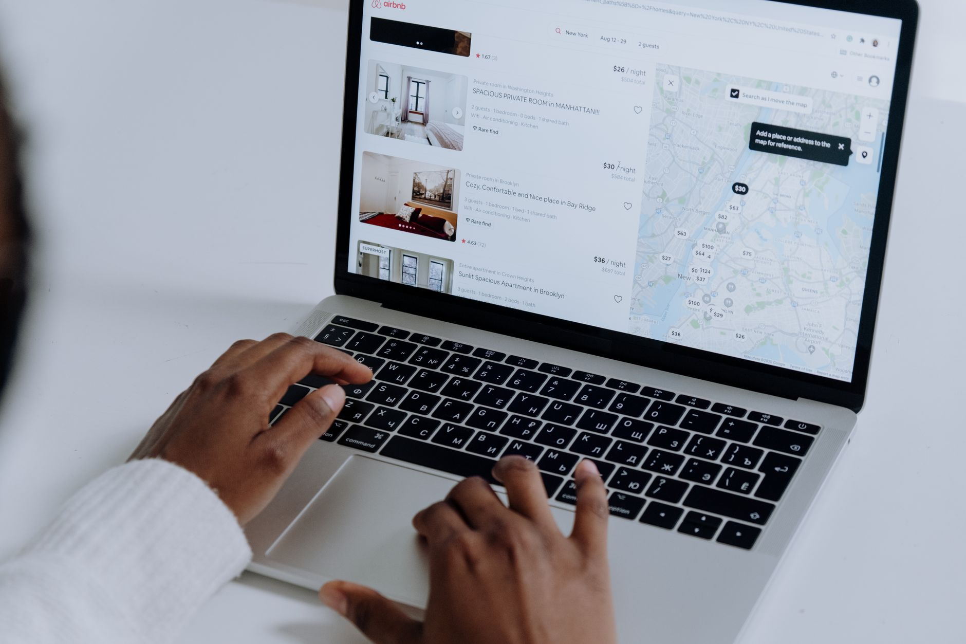 Hands type on a laptop displaying short-term-rental listings and a map.