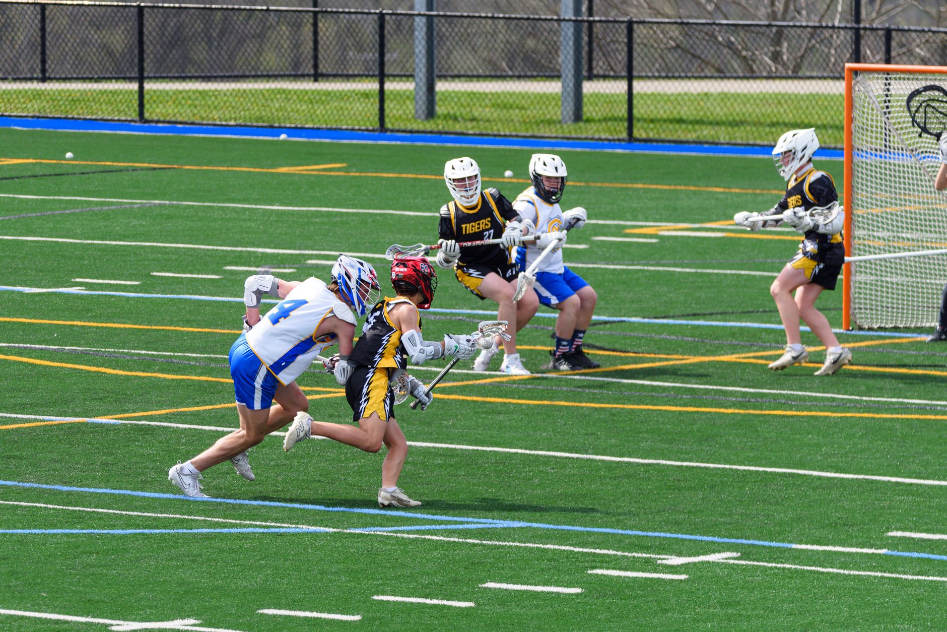 Players compete near a goal during a lacrosse game.