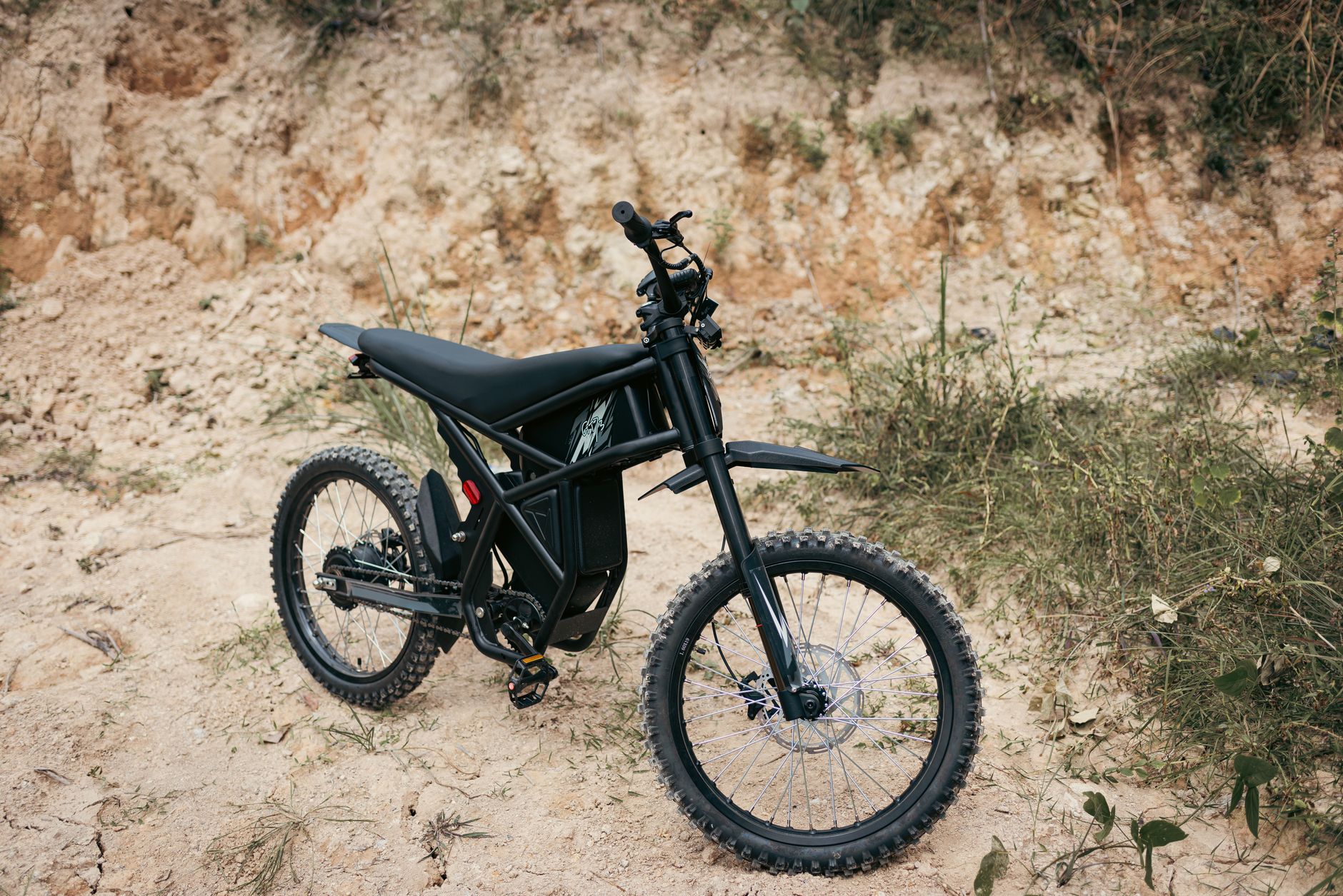 An electric off-road bike parked on rocky terrain.