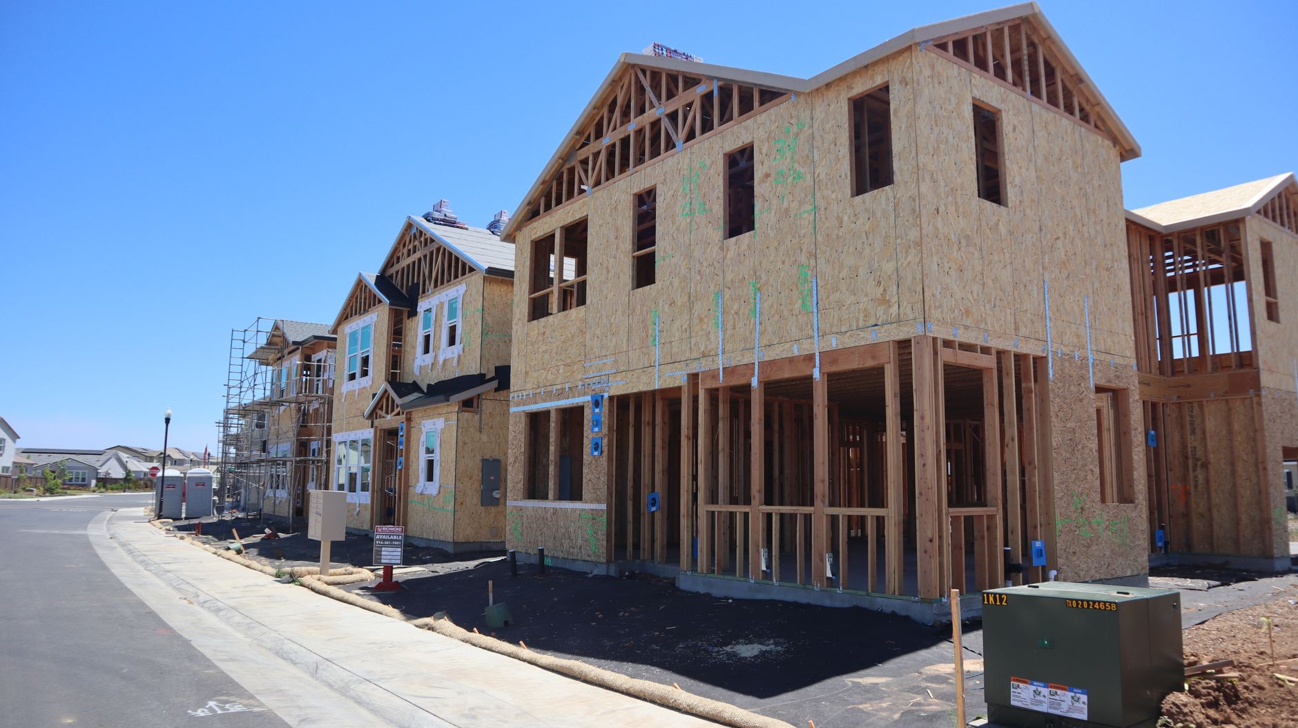 Wooden framing of several homes at a construction site.